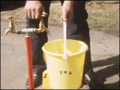 Man filling a bucket from a stand pipe